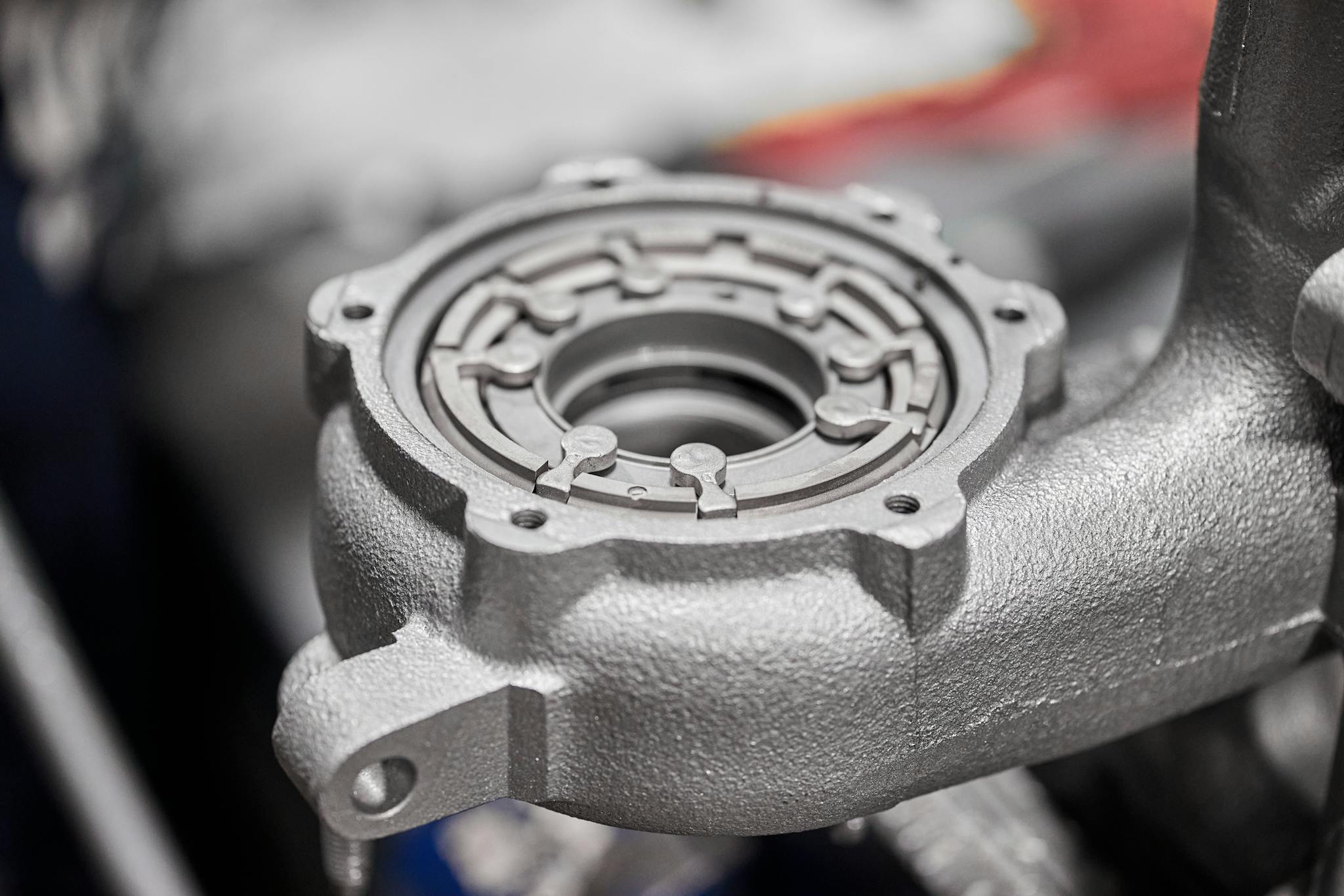 Detailed image of a metallic car component in a workshop setting, highlighting intricate metalwork.